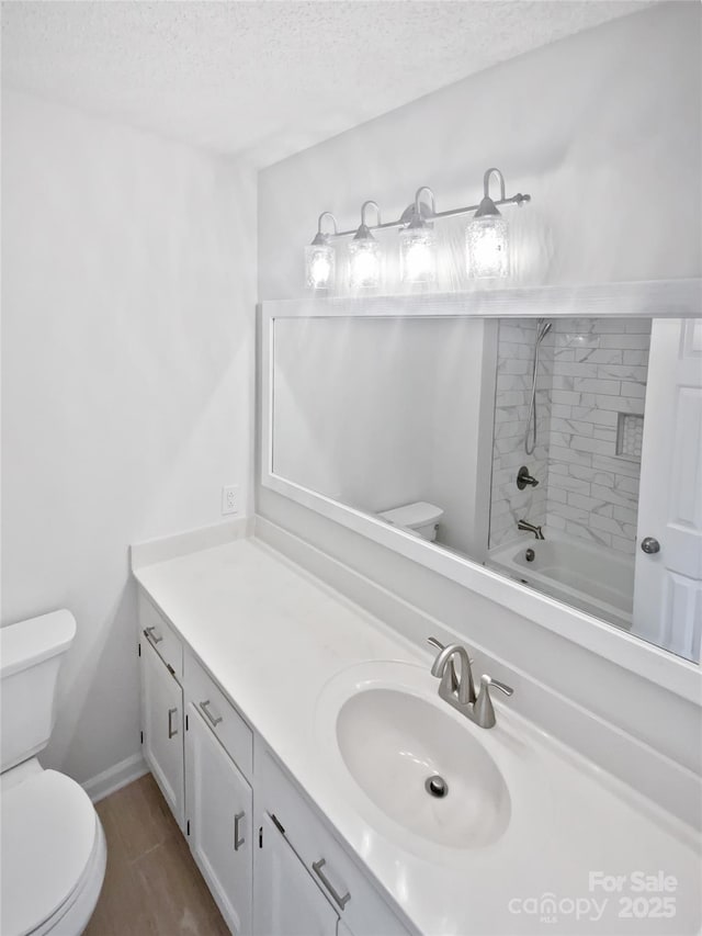 bathroom with a textured ceiling, shower / tub combination, toilet, vanity, and baseboards