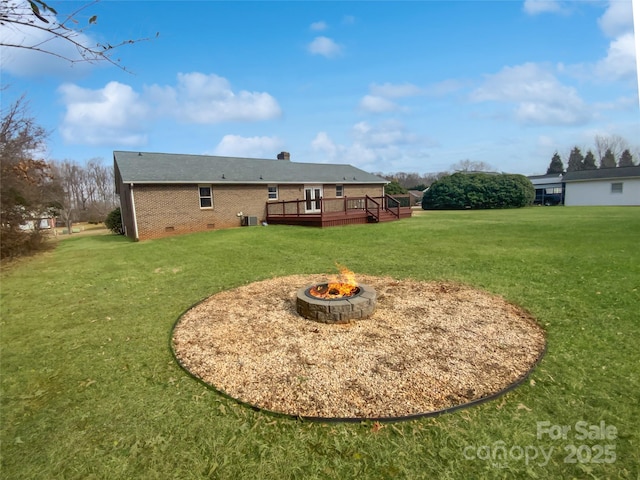 rear view of property featuring a fire pit, crawl space, a deck, a yard, and brick siding