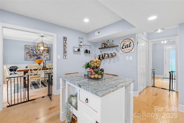 kitchen with recessed lighting, a kitchen island, white cabinets, and light wood-style floors