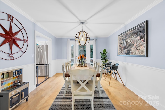 dining area with light wood-style floors, ornamental molding, and a chandelier