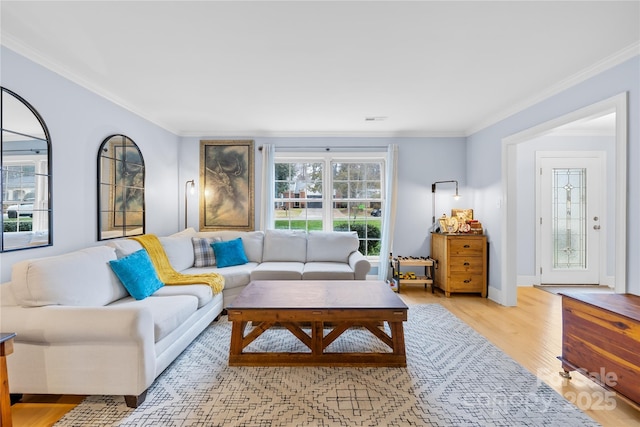 living room featuring light wood finished floors, visible vents, baseboards, and crown molding