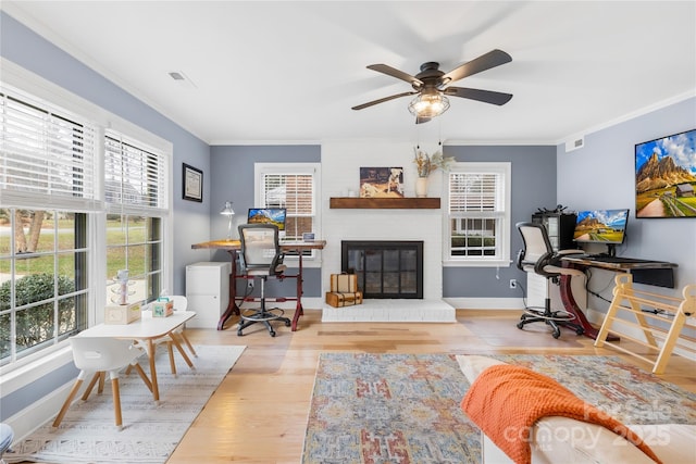 office featuring a glass covered fireplace, visible vents, crown molding, and wood finished floors