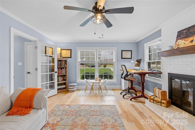 sitting room featuring a brick fireplace, baseboards, ornamental molding, and wood finished floors