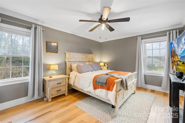 bedroom featuring light wood-type flooring, multiple windows, and crown molding