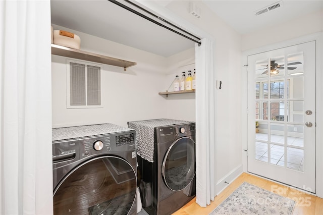 clothes washing area featuring ceiling fan, washing machine and dryer, laundry area, wood finished floors, and visible vents