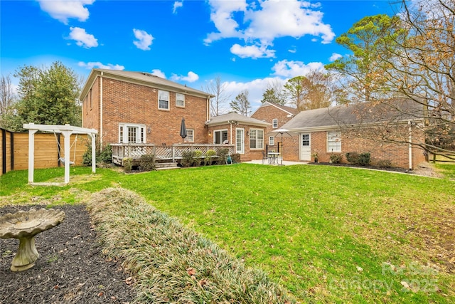 back of house with a wooden deck, a lawn, a pergola, and brick siding