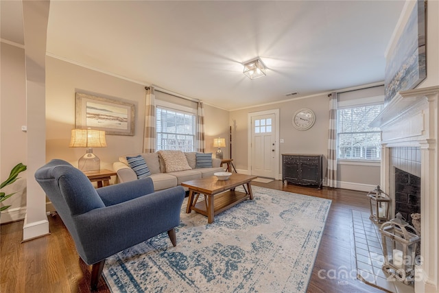 living area with visible vents, ornamental molding, wood finished floors, a fireplace, and baseboards