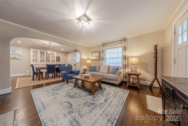 living room featuring arched walkways, crown molding, and dark wood-type flooring