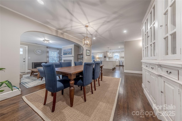 dining area featuring arched walkways, a healthy amount of sunlight, and dark wood-type flooring