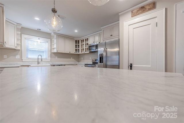 kitchen with visible vents, open shelves, light stone countertops, appliances with stainless steel finishes, and a sink