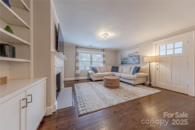 living room featuring baseboards, dark wood-type flooring, ornamental molding, and a fireplace