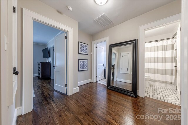 hallway featuring visible vents, baseboards, and dark wood-style floors