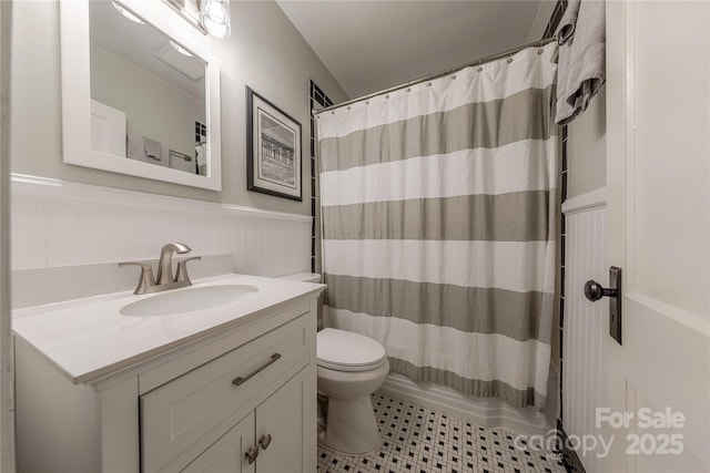 bathroom featuring a wainscoted wall, toilet, vanity, and tile patterned flooring