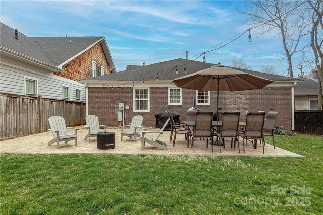 back of house featuring a yard, a fenced backyard, brick siding, and a patio