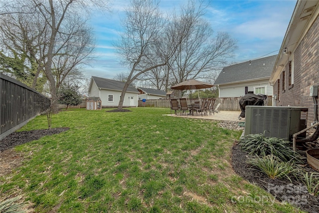 view of yard with an outbuilding, central AC unit, a patio, and a fenced backyard