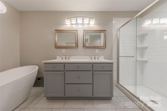 bathroom with double vanity, a stall shower, and a sink