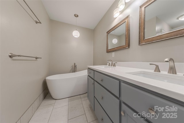 bathroom featuring a freestanding bath, double vanity, marble finish floor, and a sink