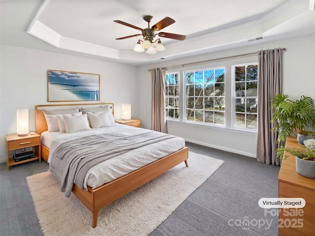 bedroom with a ceiling fan, a raised ceiling, visible vents, and baseboards