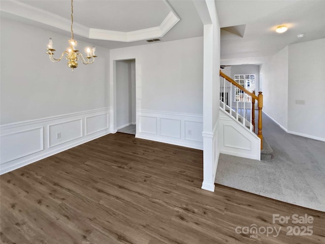 unfurnished dining area featuring visible vents, dark wood-style floors, stairway, a tray ceiling, and a chandelier