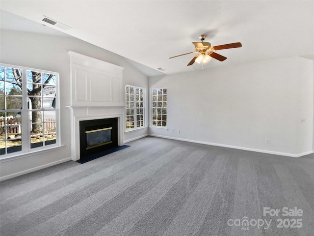 unfurnished living room with a fireplace with flush hearth, visible vents, baseboards, vaulted ceiling, and carpet