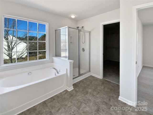 bathroom featuring a stall shower, a garden tub, and baseboards