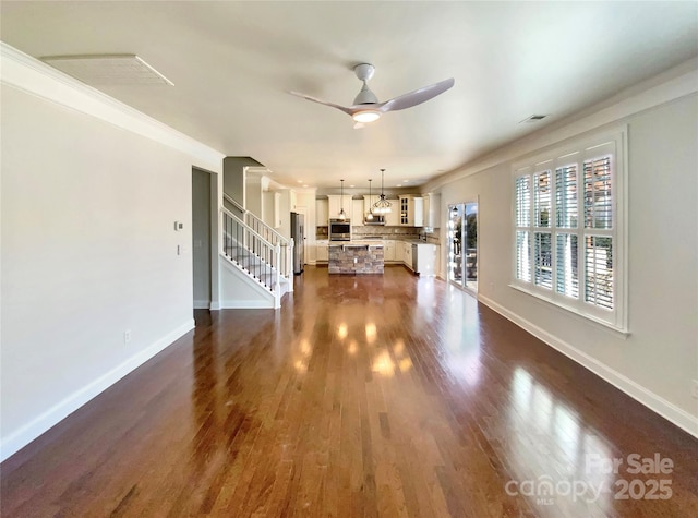 unfurnished living room with ceiling fan, dark wood-style flooring, visible vents, and baseboards