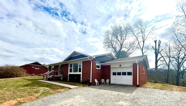 ranch-style home featuring brick siding, a front lawn, an attached garage, and gravel driveway