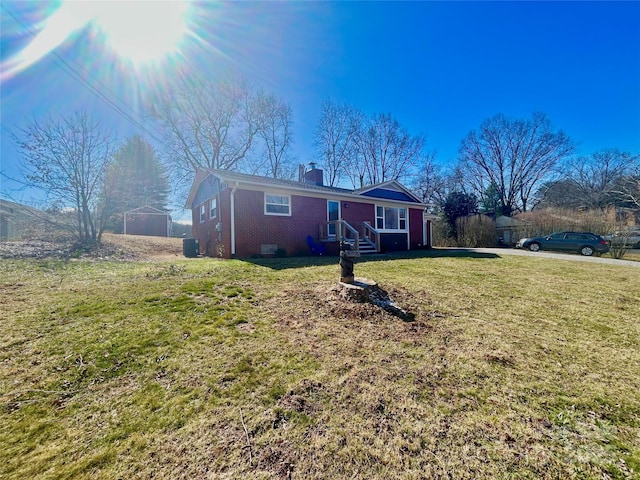 exterior space with cooling unit, brick siding, a yard, and a chimney