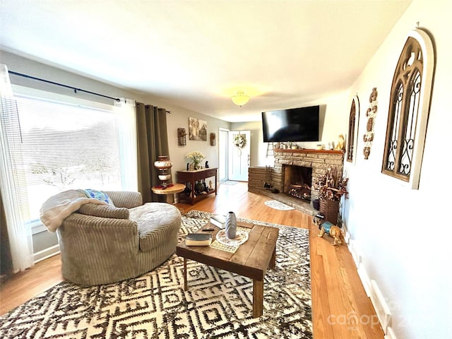 living area with a fireplace, wood finished floors, and baseboards