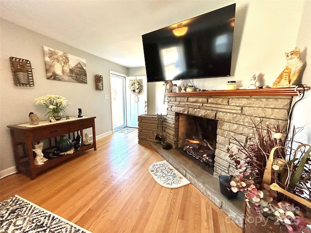 living room featuring light wood-style floors, a fireplace, and baseboards