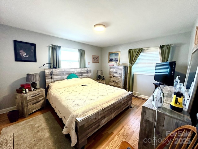 bedroom featuring wood finished floors, visible vents, and baseboards