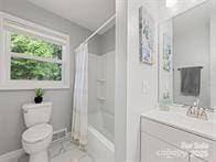 full bath featuring toilet, shower / bath combo, baseboards, and vanity