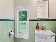 bathroom featuring tile walls and a sink