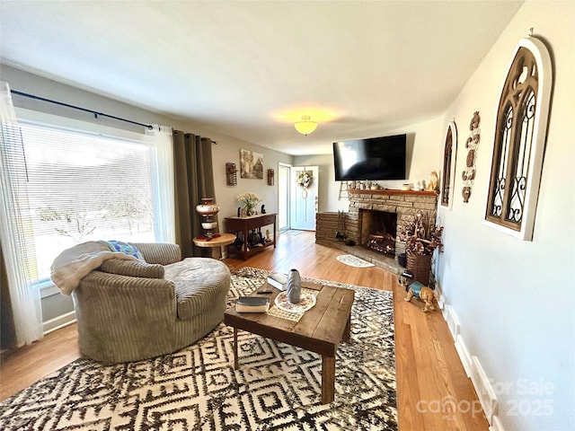 living room featuring a fireplace, baseboards, and wood finished floors