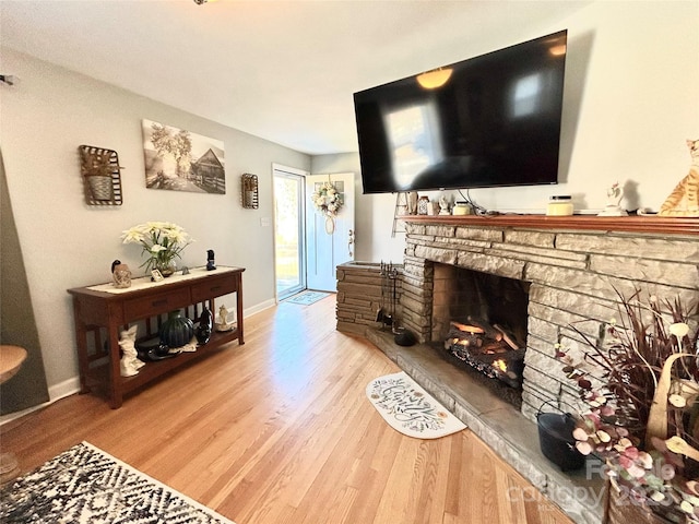 living area featuring baseboards, a fireplace, and light wood-style floors