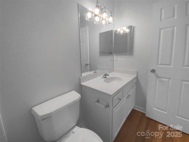 half bath with vanity, toilet, and wood finished floors