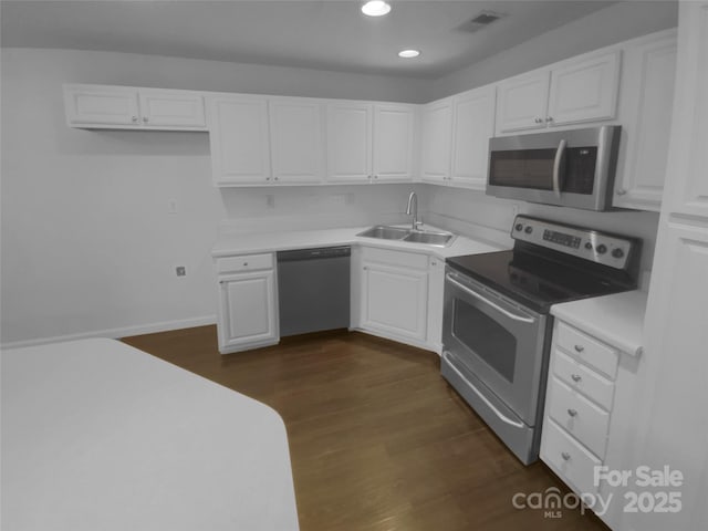 kitchen featuring visible vents, dark wood finished floors, stainless steel appliances, white cabinetry, and a sink