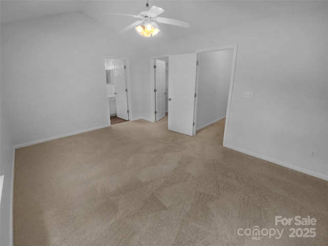 unfurnished bedroom featuring carpet floors, a walk in closet, lofted ceiling, ensuite bathroom, and baseboards