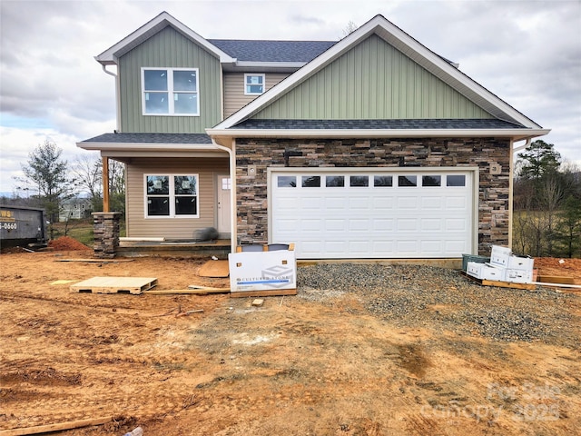 craftsman-style home with driveway, a garage, a shingled roof, stone siding, and board and batten siding