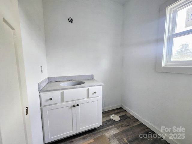 bathroom featuring baseboards, wood finished floors, and vanity