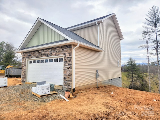 view of home's exterior featuring a garage, driveway, a shingled roof, and stone siding