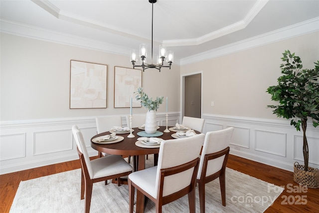 dining area featuring an inviting chandelier, wood finished floors, and wainscoting