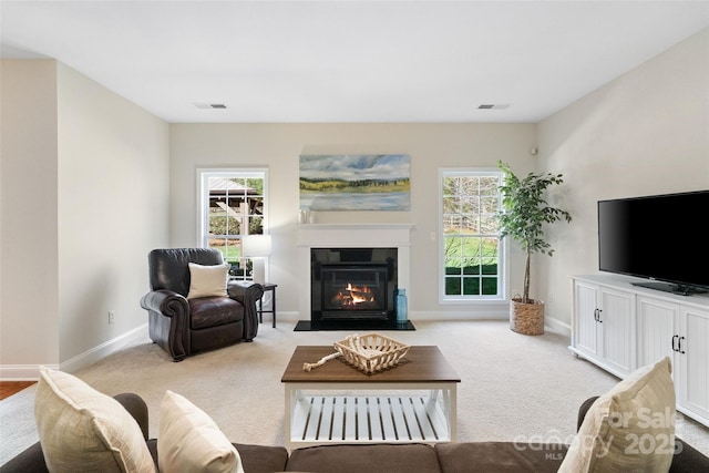 living area with visible vents, carpet flooring, baseboards, and a fireplace with flush hearth