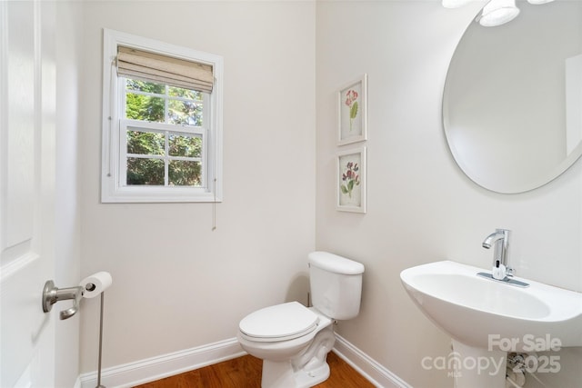 bathroom with a sink, baseboards, toilet, and wood finished floors