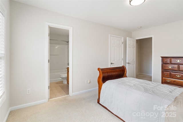 bedroom with light carpet, ensuite bath, and baseboards