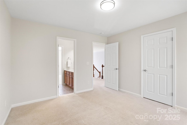 unfurnished bedroom featuring baseboards, light carpet, and connected bathroom