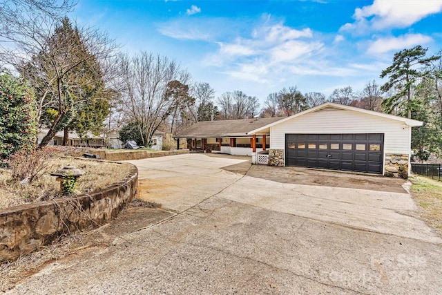 view of front facade featuring driveway, stone siding, and an attached garage