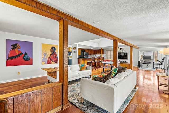 living area with baseboards, a textured ceiling, and hardwood / wood-style floors