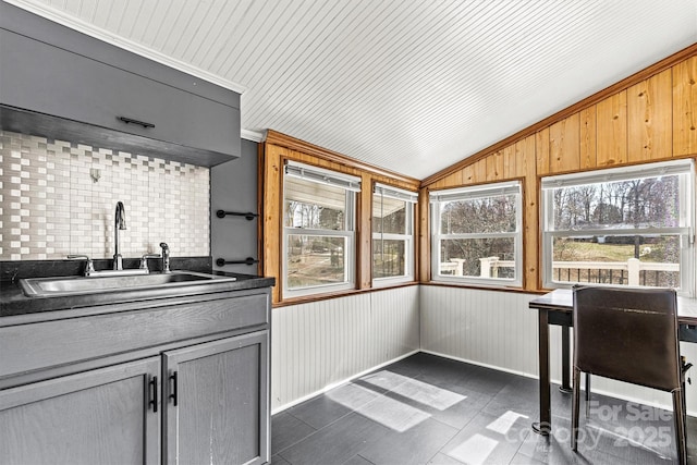 kitchen with gray cabinets, dark countertops, vaulted ceiling, and a sink