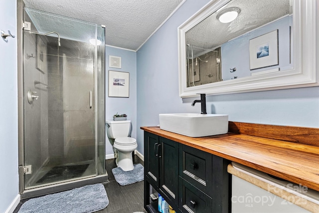 full bathroom with baseboards, toilet, a textured ceiling, vanity, and a shower stall